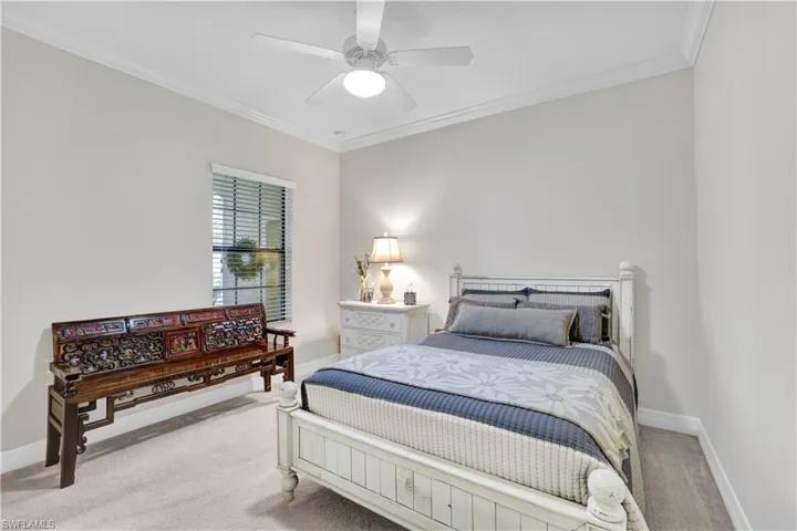 Bedroom with ornamental molding, light colored carpet, and ceiling fan