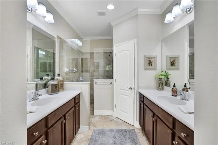 Full bath featuring crown molding, two vanities, walk in shower, and recessed lighting