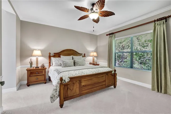 Bedroom with ornamental molding, light colored carpet, and a ceiling fan