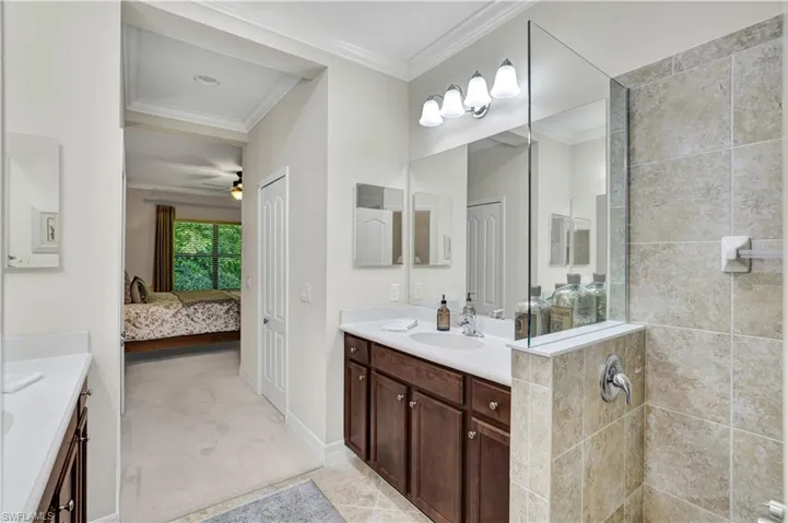 Bathroom featuring connected bathroom, crown molding, two vanities, light colored carpet, and walk in shower