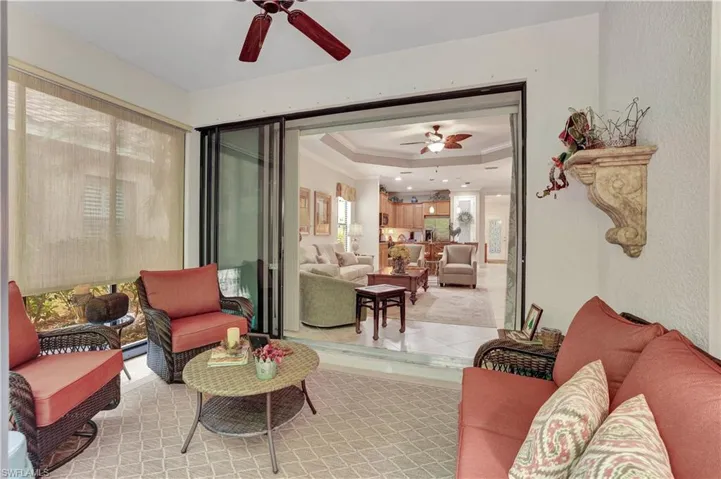 Living room with a raised ceiling, a ceiling fan, and ornamental molding