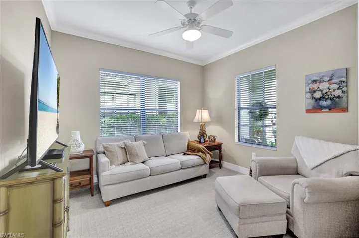 Living area featuring carpet floors, crown molding, and ceiling fan
