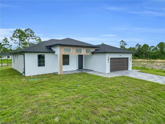 Prairie-style house featuring stucco siding, an attached garage, decorative driveway, and a front lawn