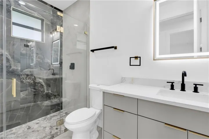 Full bath featuring vanity and a marble finish shower