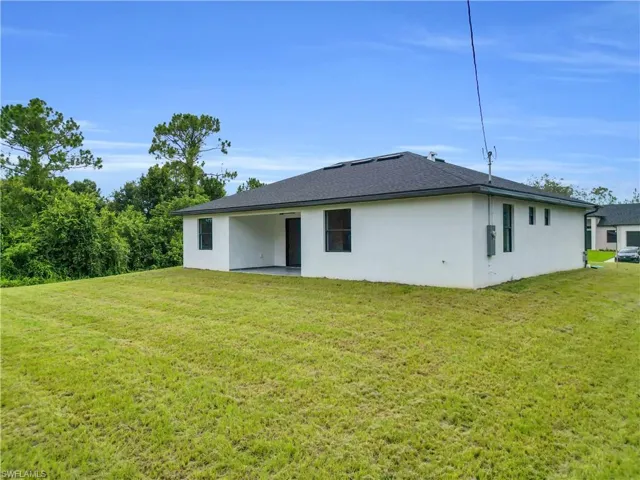 Back of property with a patio area, a lawn, and stucco siding