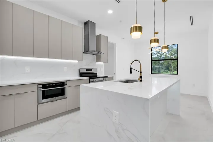 Kitchen with light stone countertops, gray cabinets, tasteful backsplash, modern cabinets, and stainless steel appliances