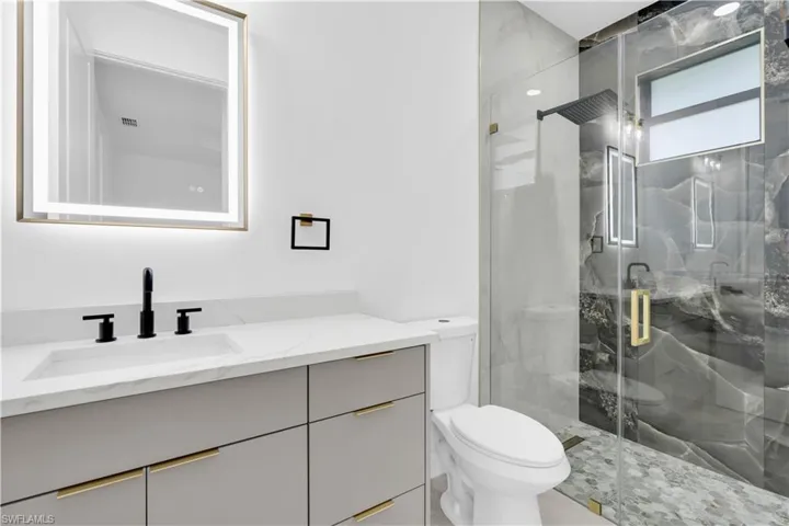 Full bath featuring vanity and a marble finish shower
