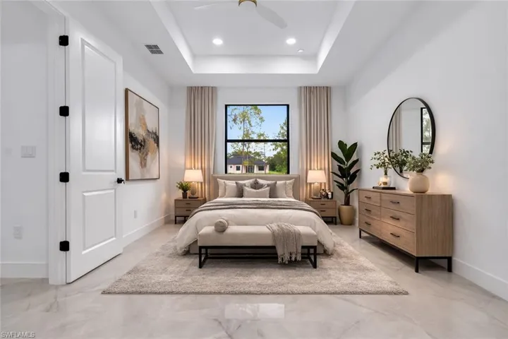 Bedroom with a raised ceiling, ceiling fan, recessed lighting, and light marble finish flooring