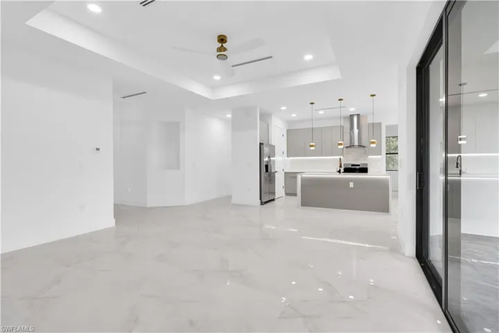 Unfurnished living room featuring a ceiling fan, a raised ceiling, and recessed lighting