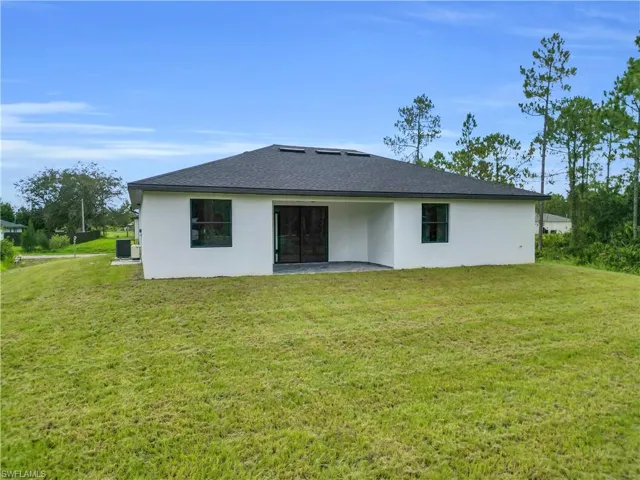 Rear view of property featuring a lawn, stucco siding, and a patio area