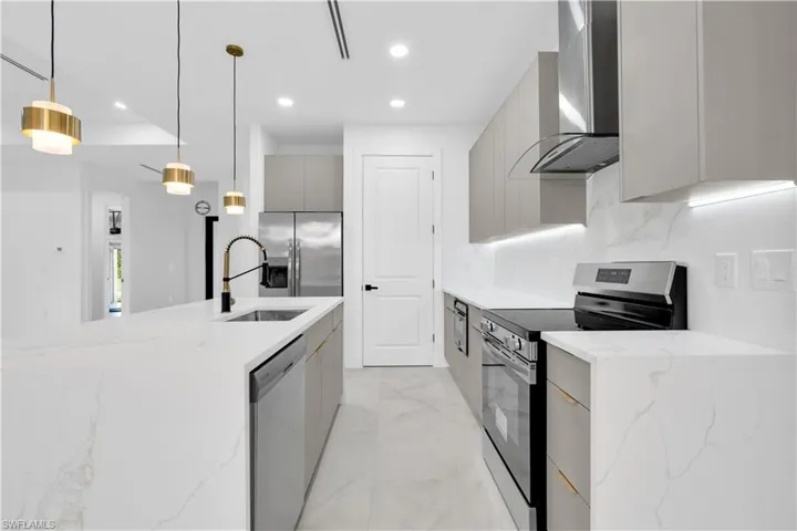 Kitchen with light stone countertops, stainless steel appliances, modern cabinets, and gray cabinetry