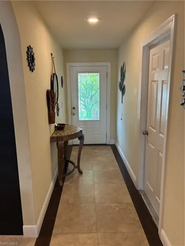 Entryway featuring a white door with decorative glass, recessed lighting, and a neutral wall color