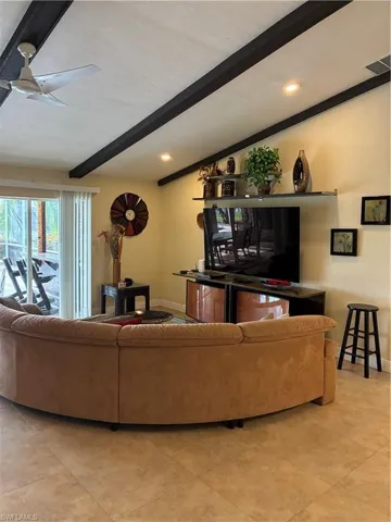 Living area featuring vaulted ceilings with exposed dark beams, recessed lighting, and a ceiling fan