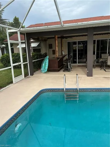 Screened-in pool area featuring a rectangular pool with integrated steps and a mosaic tile border