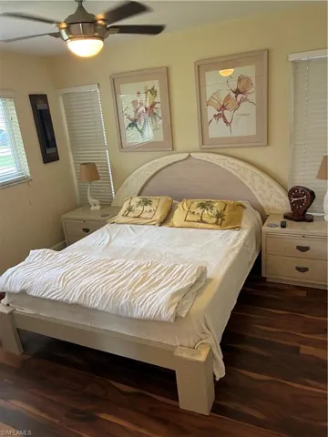 Spacious room featuring wood-finish flooring, a ceiling fan with integrated lighting, window blinds, and a light-toned bed frame with an arched headboard