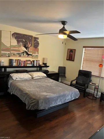 Spacious room featuring wood-finish flooring, a ceiling fan with integrated lighting, and a window with horizontal blinds