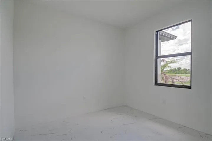 Spare room featuring marble look tiles and baseboards