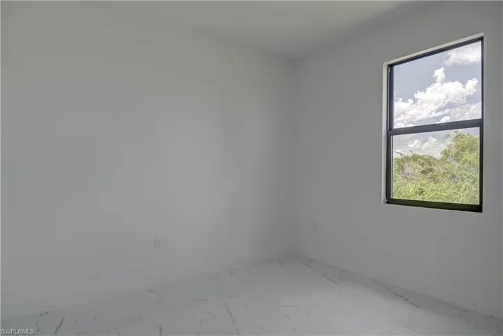 Spare room featuring light marble finish flooring and baseboards