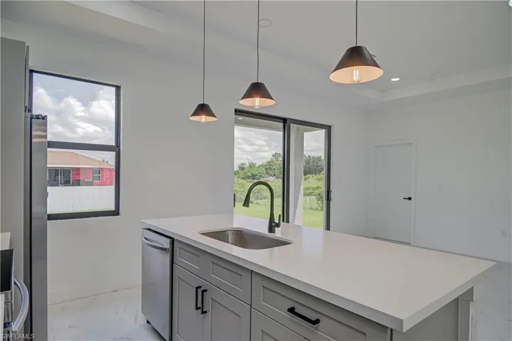 Kitchen featuring light marble finish floors, light countertops, gray cabinets, recessed lighting, and pendant lighting