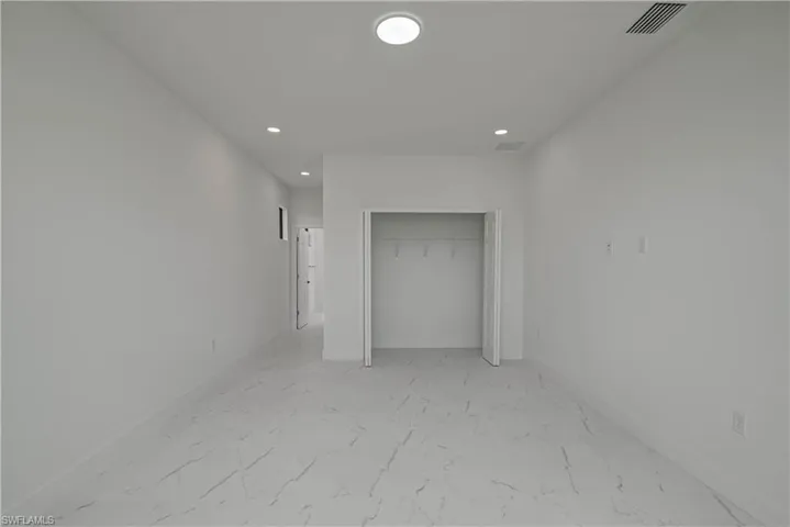 Unfurnished bedroom featuring light marble finish floors, recessed lighting, and a closet
