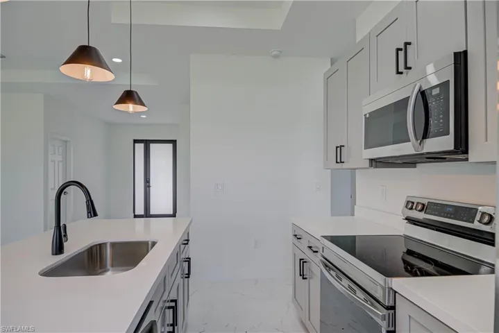 Kitchen with appliances with stainless steel finishes, light marble finish flooring, decorative light fixtures, light countertops, and recessed lighting