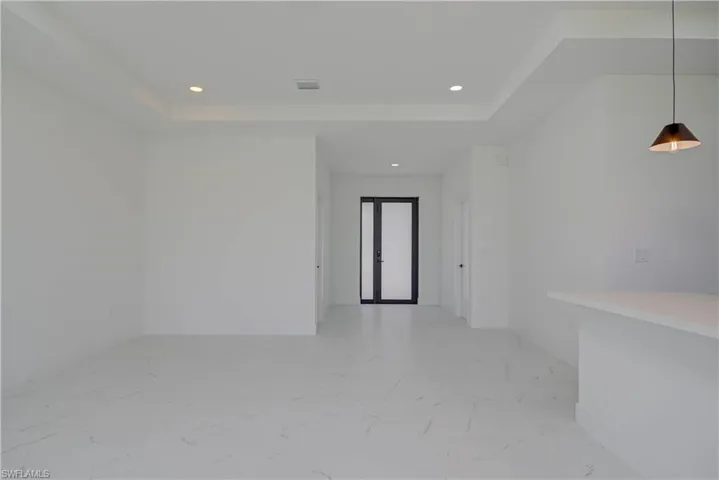 Unfurnished room with recessed lighting, light marble finish flooring, and a raised ceiling