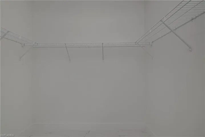 Spacious closet featuring light marble finish flooring