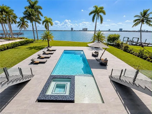 Expansive waterside property featuring a rectangular pool, integrated spa, and an additional shallow water lounging area