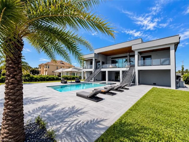 Modern architecture with multiple balconies, a pristine swimming pool, and extensive paved patio