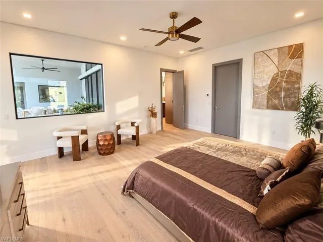 Light wood-finish flooring with recessed ceiling lights and a ceiling fan