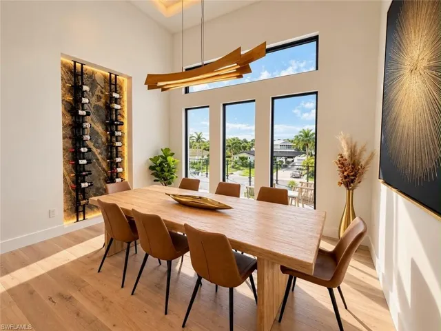Modern chandelier, built-in wine rack with stone finish, wood-finish flooring, high ceilings, and multiple transom windows