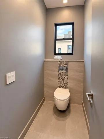 Modern wall-mounted toilet with a mosaic tile accent wall