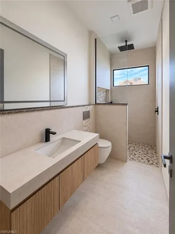 Floating vanity with a rectangular basin, matte black faucet, and wood-finish cabinetry