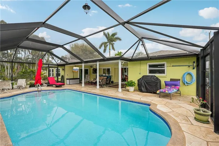 Outdoor pool featuring glass enclosure, a sunroom, a patio area, and a grill