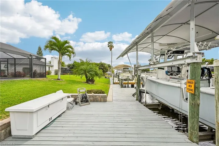 Dock area with a yard, boat lift, a water view, and glass enclosure