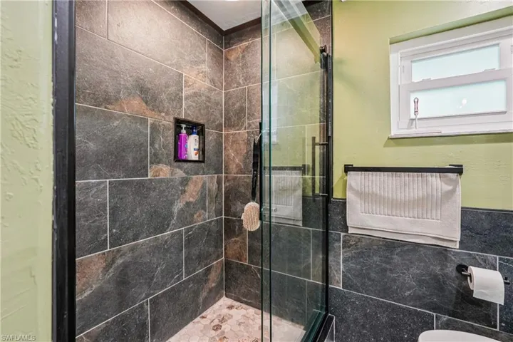 Bathroom featuring a stall shower, tile walls, and wainscoting