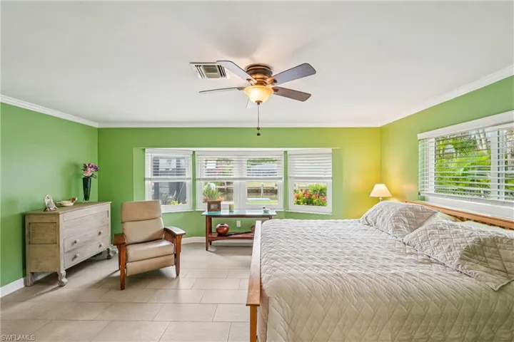 Bedroom featuring a ceiling fan, ornamental molding, and light tile patterned flooring