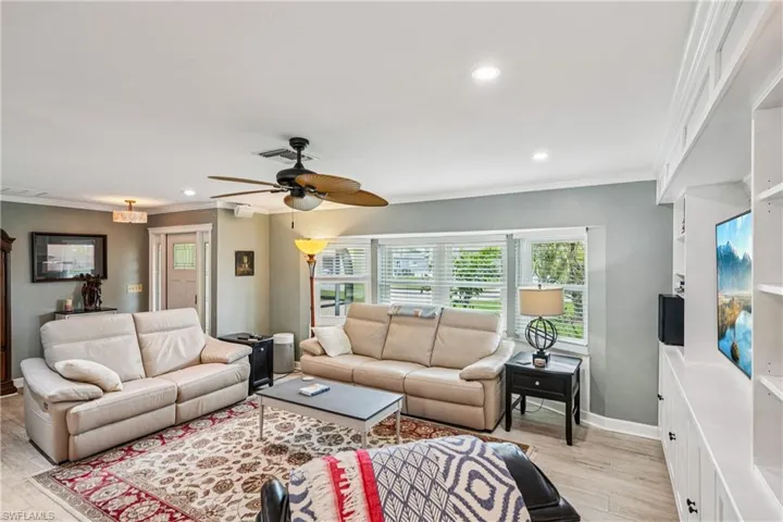 Living room with a ceiling fan, crown molding, recessed lighting, and light wood-style floors