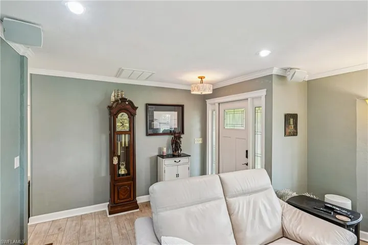 Living area featuring light wood-style flooring, ornamental molding, and recessed lighting