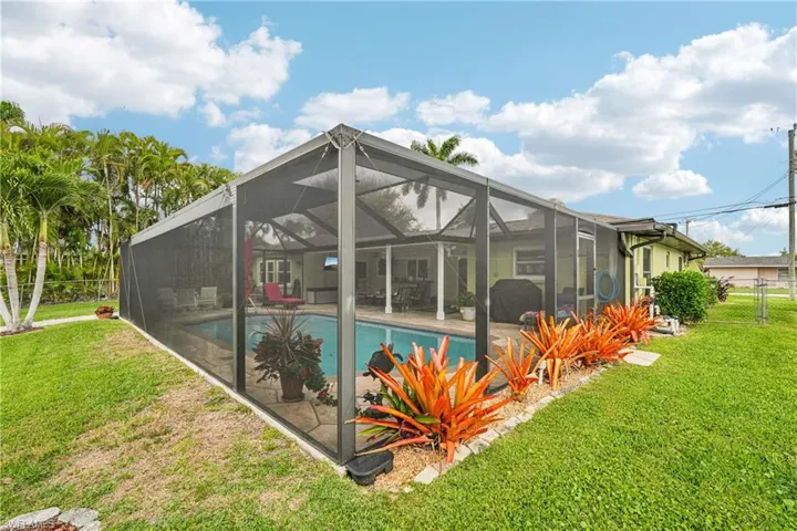 Rear view of house with an outdoor pool, a lanai, and a sunroom