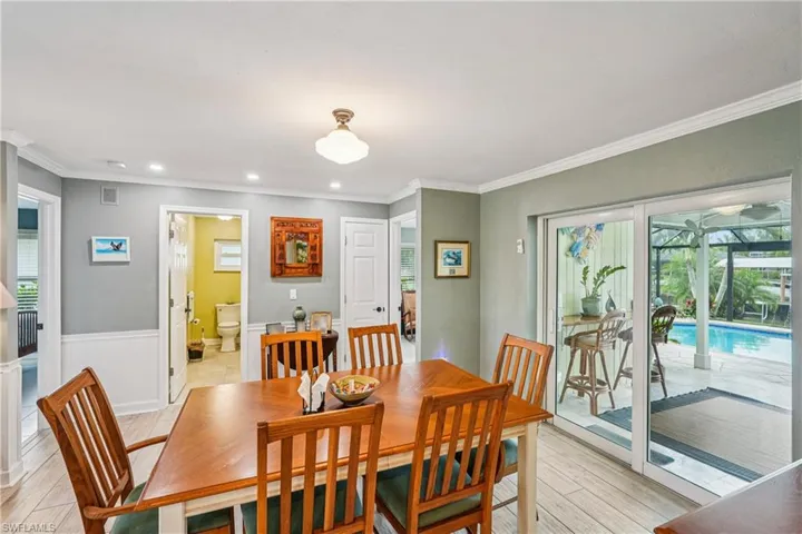 Dining room with crown molding, a wainscoted wall, recessed lighting, and light wood-type flooring