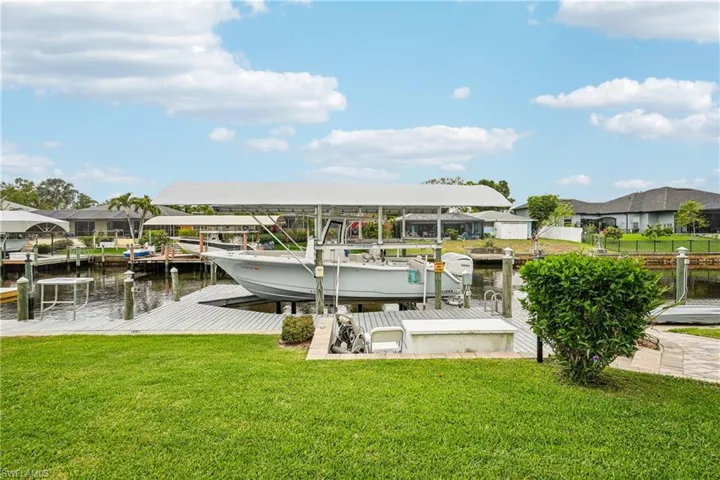 Dock area with a lawn, boat lift, a water view, and a residential view