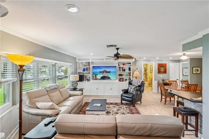 Living room featuring crown molding, light wood-type flooring, ceiling fan, and recessed lighting