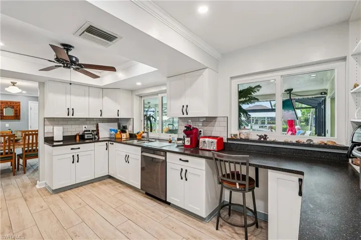 Kitchen with crown molding, a ceiling fan, white cabinetry, dishwasher, and light wood-style flooring