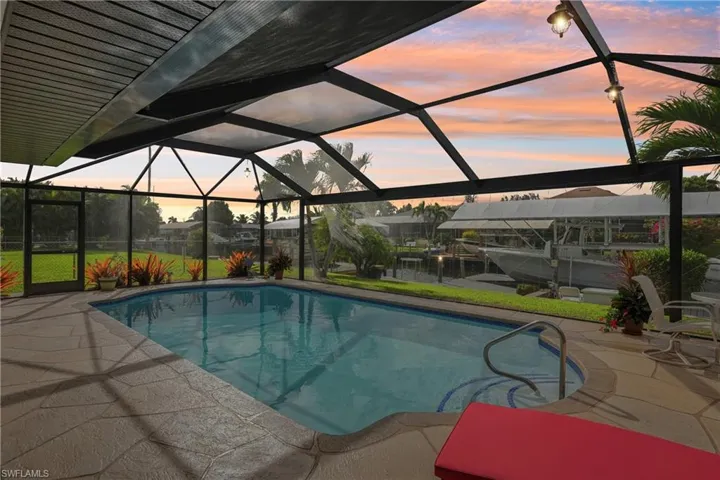 Pool at dusk featuring a sunroom, glass enclosure, and an outdoor pool