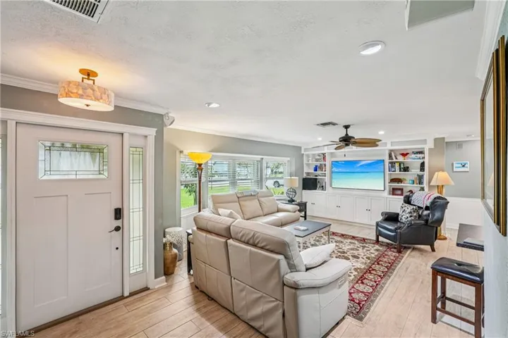 Living area with light wood finished floors, recessed lighting, ornamental molding, a textured ceiling, and ceiling fan