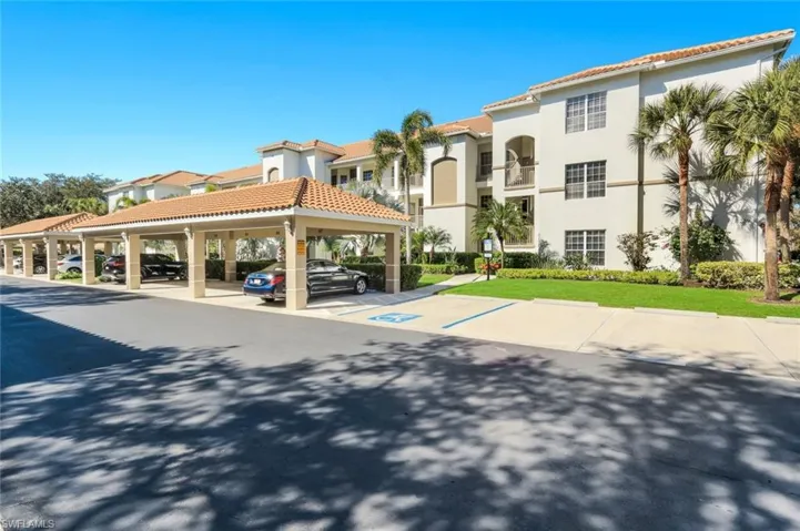 View of building exterior featuring covered and uncovered parking