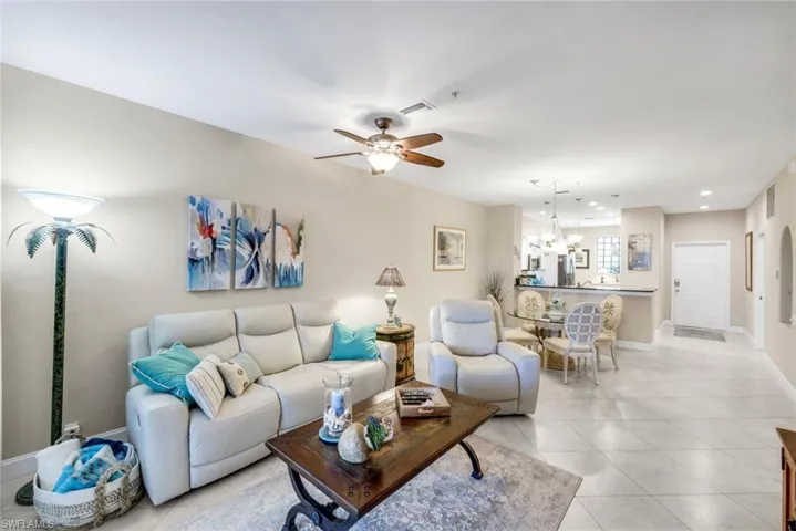 Living area with ceiling fan, light tile patterned flooring, and suspended lighting