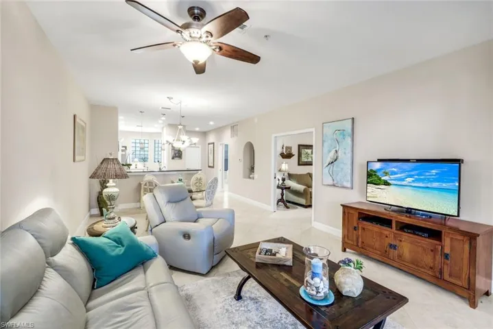 Living area with ceiling fan, arched walkways, light tile patterned floors, and recessed lighting