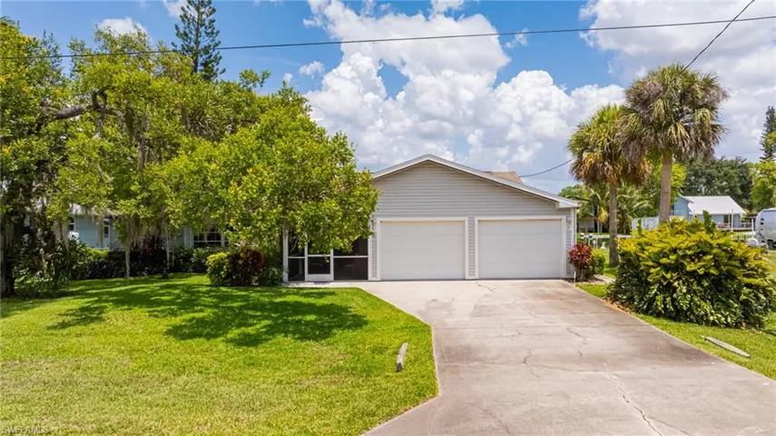 View of front of home featuring concrete driveway, a front lawn, and an attached garage